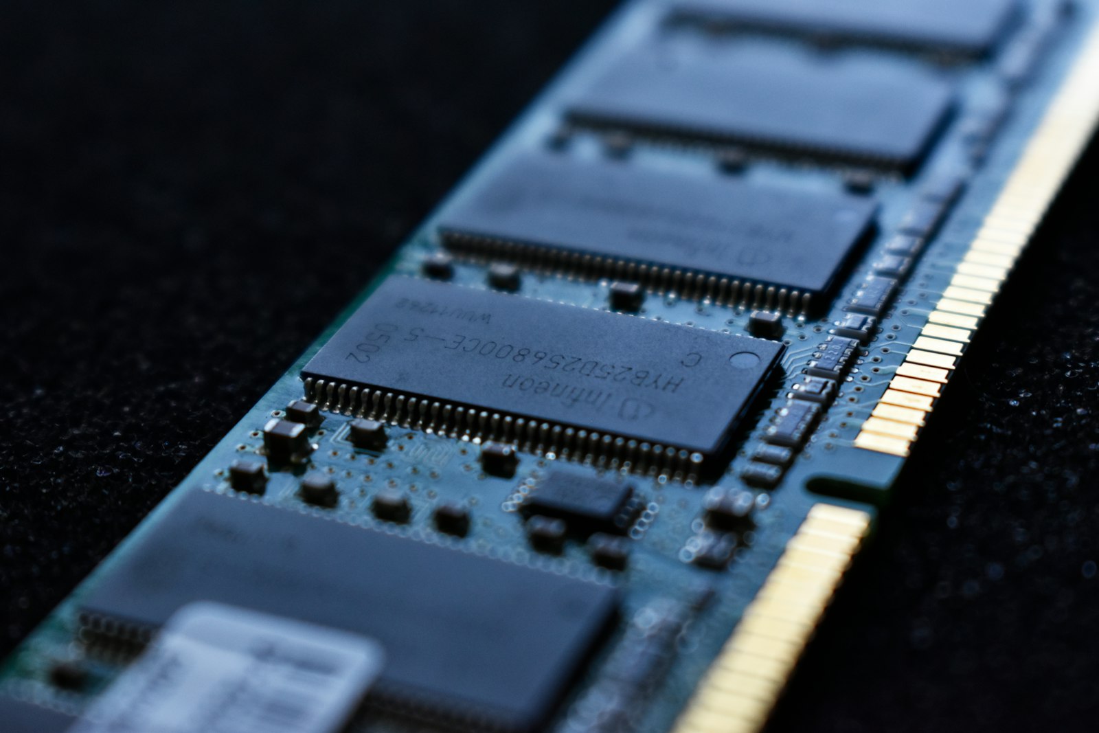Macro photograph of a DDR memory module, its chips lit in cool blue against a dark background