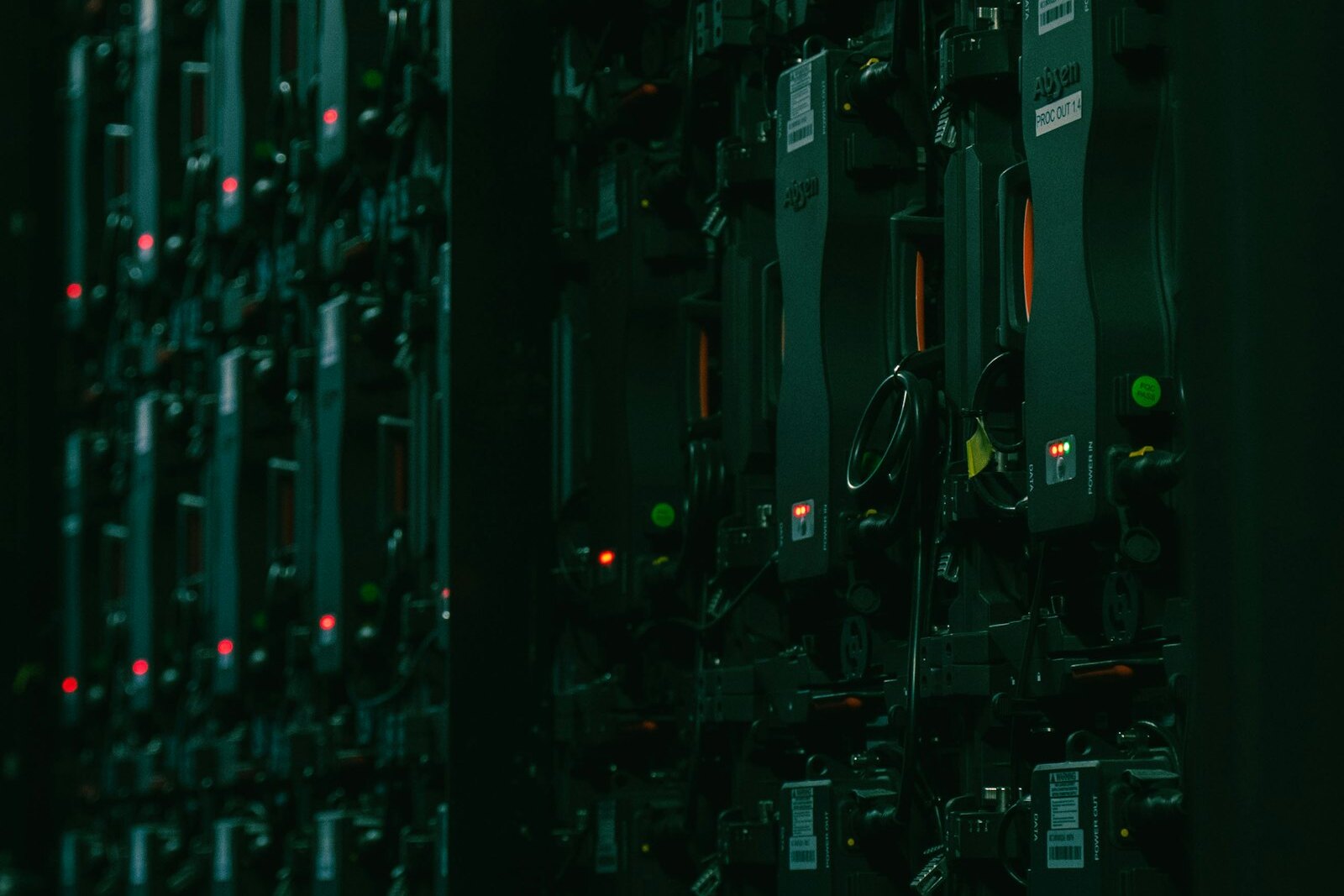Rows of densely packed compute hardware in a dark server room, status LEDs glowing red and green